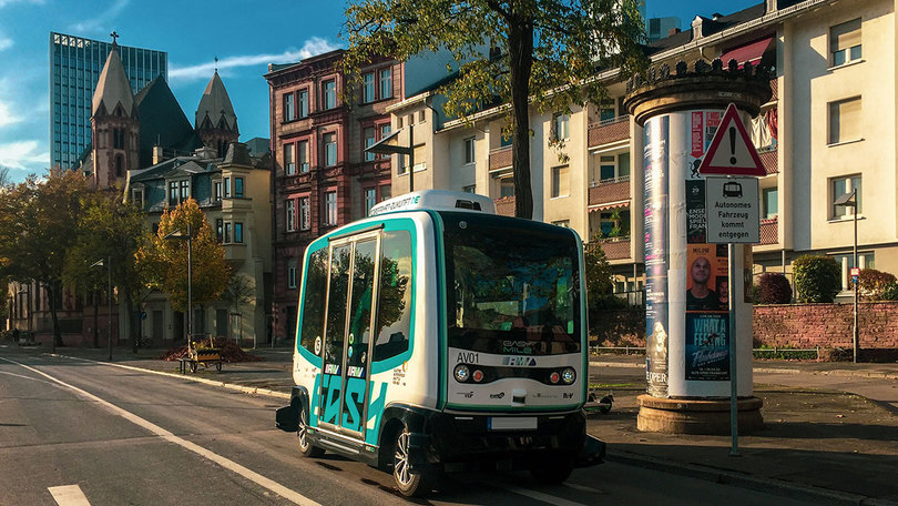 autonomen Kleinbus auf ein einer Straße im Hintergrund Häuser