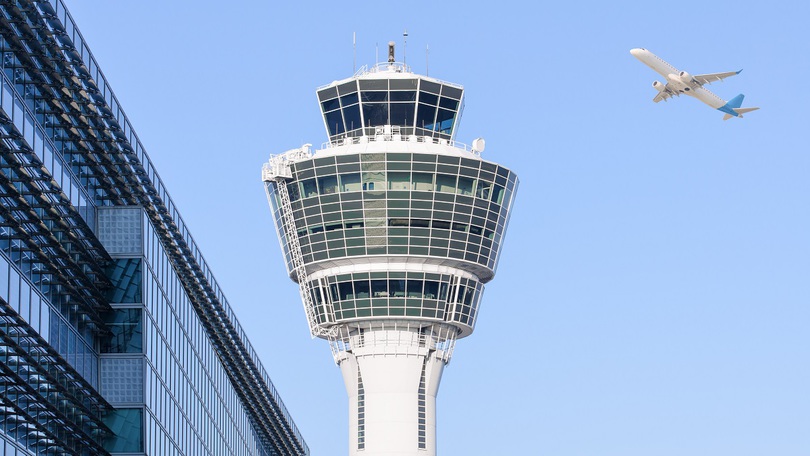 Ein Flugzeug fliegt an einem Flughafen-Tower vorbei